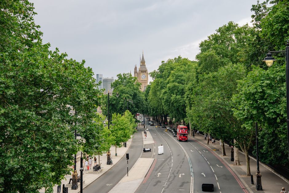 View of a historic London building with ornate architectural details, including decorative cornices and domes, situated on a busy street near a station entrance. In the foreground, a red and white rou